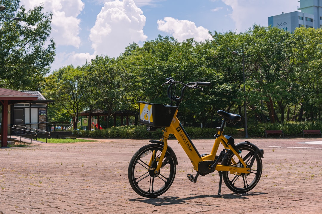 A yellow bicycle parks on a gravelly road.